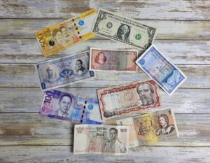 Billetes de diferentes monedas sobre una mesa de madera representando el tipo de cambio peso-dólar