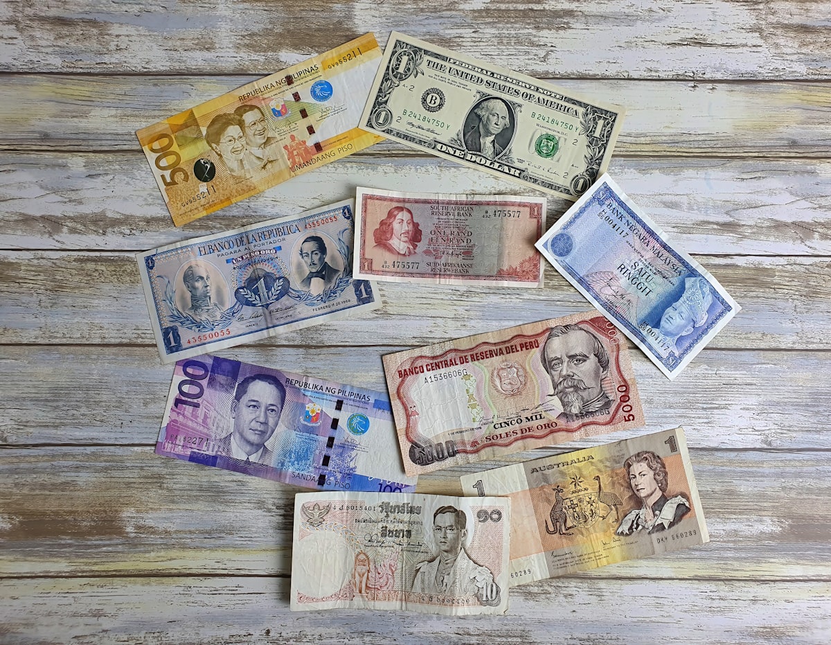 Billetes de diferentes monedas sobre una mesa de madera representando el tipo de cambio peso-dólar