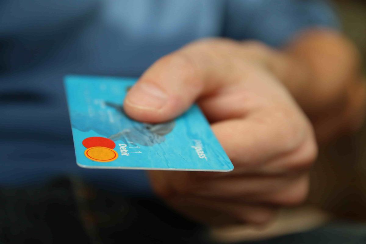 Mano ofreciendo una tarjeta de débito contactless, símbolo de los bancos digitales como Nu y Revolut que compiten en México